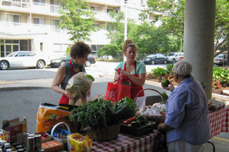 People shopping at outdoor farmers market table